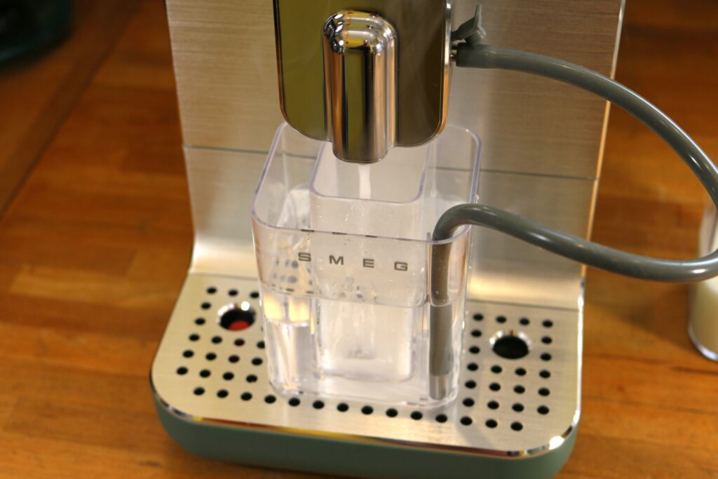 La cafetière expresso avec broyeur SMEG BCC13. En détail, le réservoir à grains de café. Le nettoyage de la buse après écoulement d'une boisson lactée