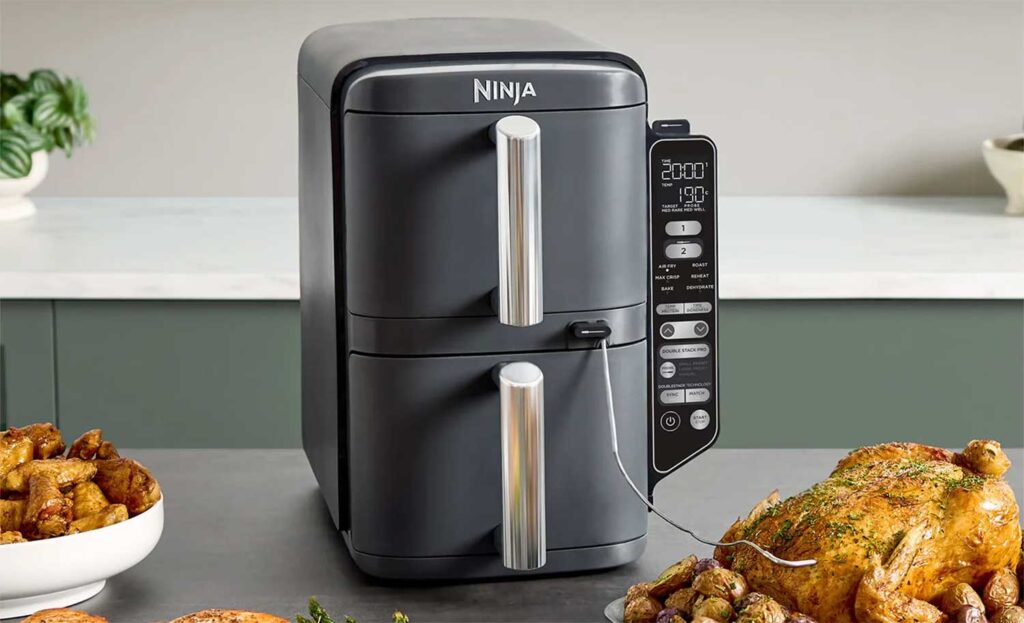Le Ninja Double Stack XL 9,5 L SL451EU posé sur un plan de travail avec des aliments cuisinés autour