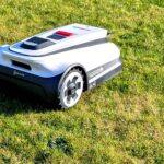 Robot tondeuse sur l'herbe prêt pour changer ses lames pour le printemps 2026