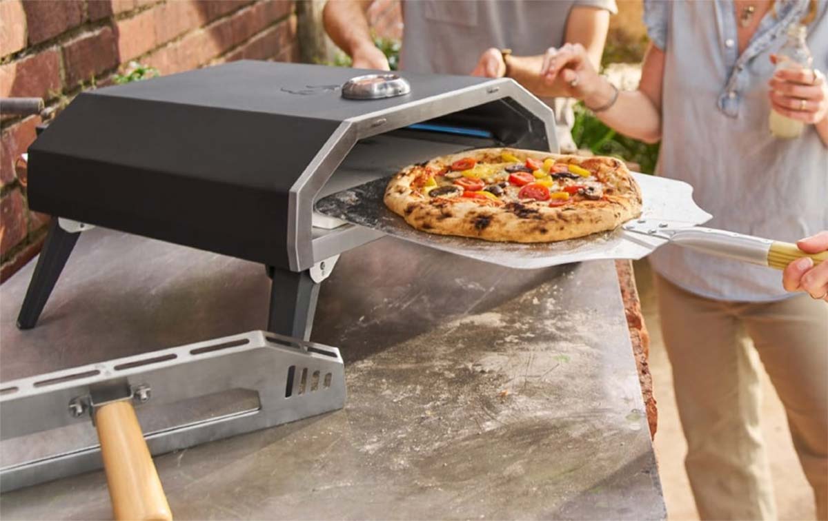 Four à pizza à gaz Lidl en fonctionnement, avec une pizza qui sort du four porte ouverte