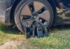 Les quatre compresseurs portatifs au pied d’un pneu de Tesla Model 3 Grande Autonomie, prêts pour le test de gonflage.