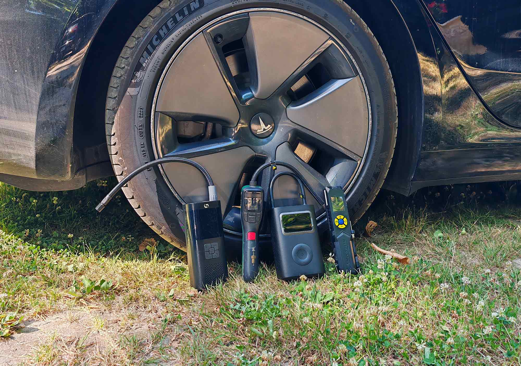 Les quatre compresseurs portatifs au pied d’un pneu de Tesla Model 3 Grande Autonomie, prêts pour le test de gonflage.