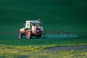 Tracteur pulvérisant des pesticides sur un champ agricole en pleine journée