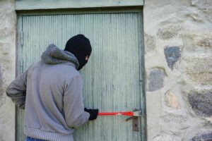 Personne tentant de forcer une porte d’entrée avec un pied de biche