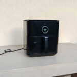 Airfryer posé sur un balcon, branché à une rallonge électrique extérieure