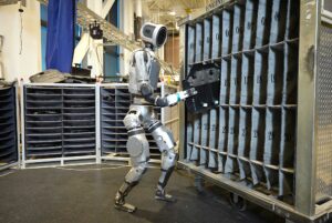 Robot Atlas de Boston Dynamics interagissant avec une armoire dans une usine, montrant sa précision et son agilité.