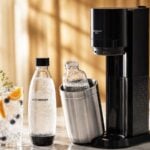 Machine à soda SodaStream Duo avec bouteilles réutilisables et verre d'eau gazeuse aux fruits frais sur comptoir cuisine été 2026