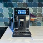 Machine à café Delonghi PrimaDonna Aromatic posée sur un plan de travail en cuisine