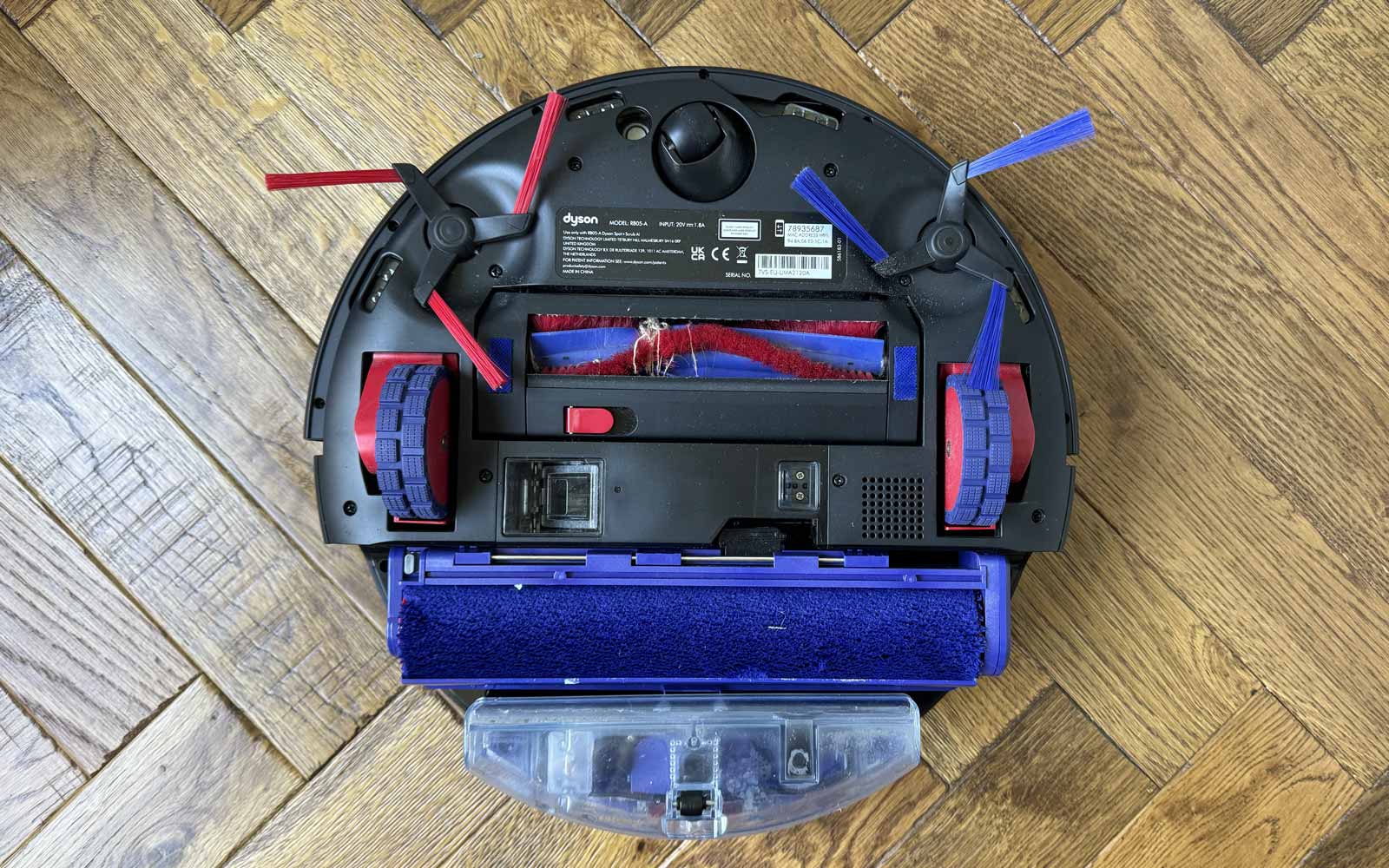 Vue du dessous du Dyson Spot+Scrub Ai montrant le rouleau de lavage, la brosse centrale et les brosses latérales