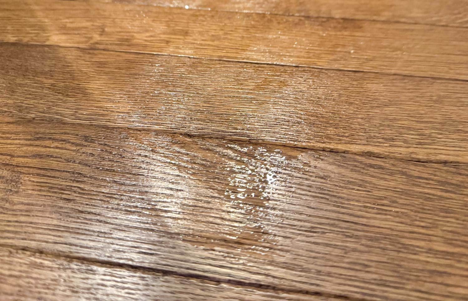 Petite flaque d’eau laissée sur parquet après le passage du Dyson V16 Submarine.