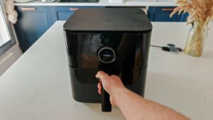 Une main ouvre le tiroir d'un airfryer Xiaomi Smart Air Fryer posé sur un îlot de cuisine