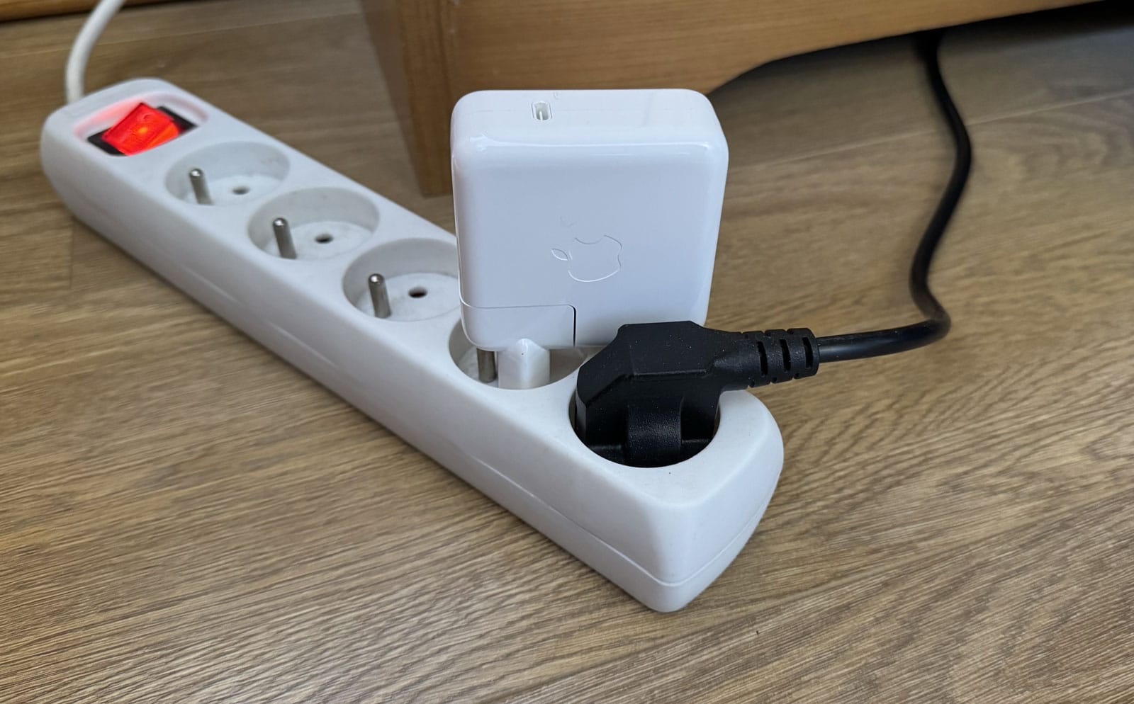 Chargeur Apple 70 W branché sur une multiprise pour évaluer l’encombrement