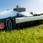 Robot tondeuse Mammotion Luba 3 AWD en action sur une pelouse pentue, avec grandes roues et châssis tout-terrain.