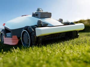 Robot tondeuse Mammotion Luba 3 AWD en action sur une pelouse pentue, avec grandes roues et châssis tout-terrain.
