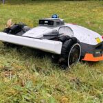 Robot tondeuse Mammotion Luba 3 AWD 4x4 en train de grimper une pente raide en utilisant ses suspensions indépendantes.