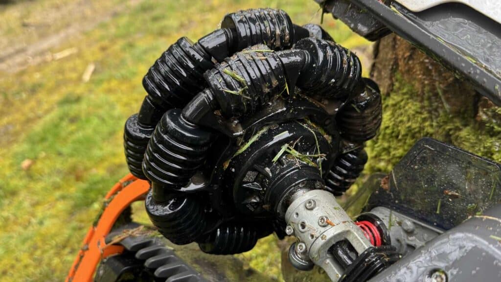 Roue avant omnidirectionnelle du robot tondeuse Mammotion Luba 3 AWD totalement encrassée par de la terre humide.