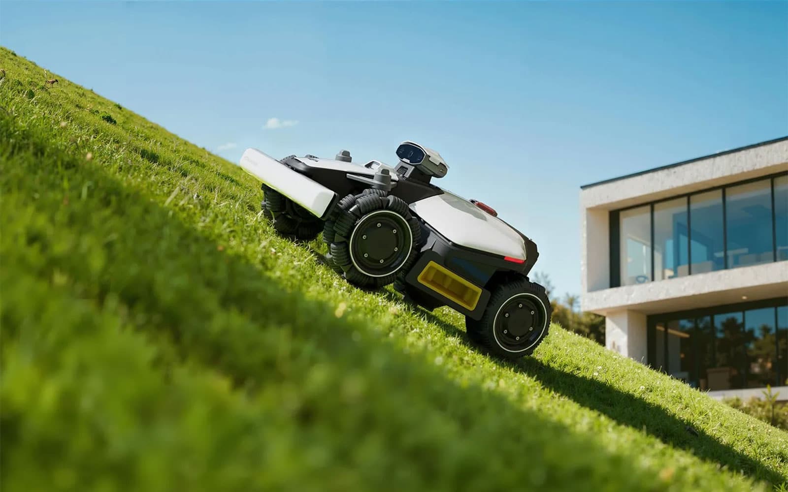 Robot tondeuse Mammotion Luba mini 2 AWD compact, en train de tondre près d’une bordure de jardin.