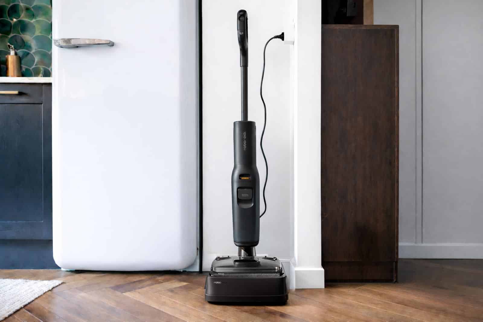 Aspirateur laveur Roborock F25 Ace Pro dans sa base de recharge posé sur parquet dans une cuisine