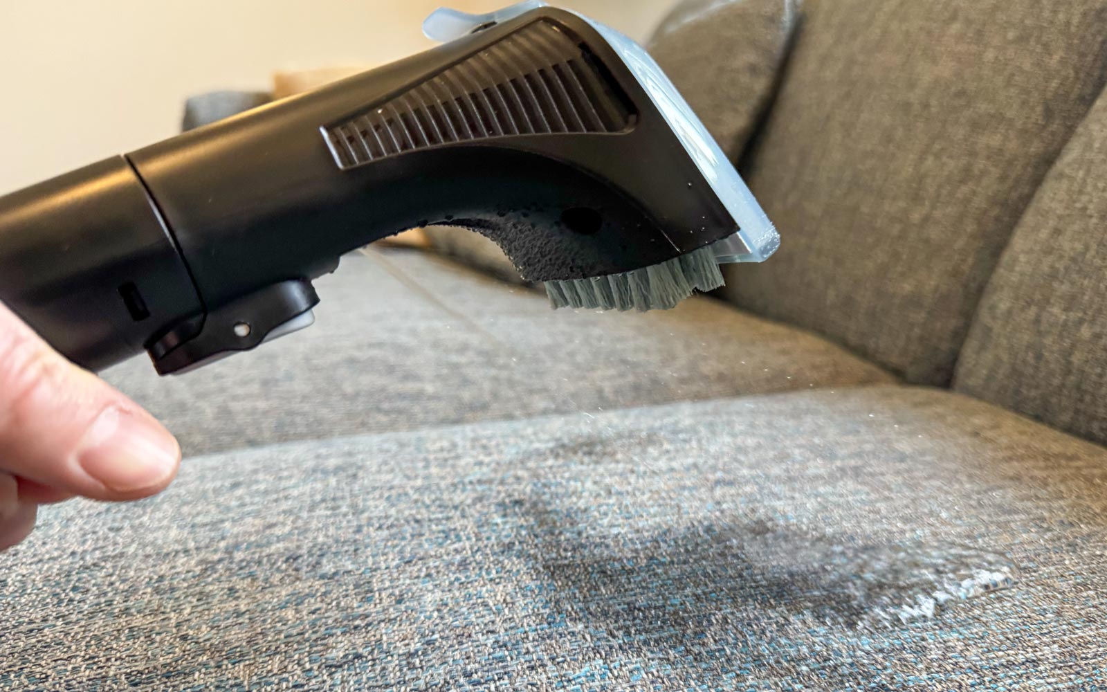 Pulvérisation d’eau et de détergent sur un canapé avec le Rowenta Clean It Compact