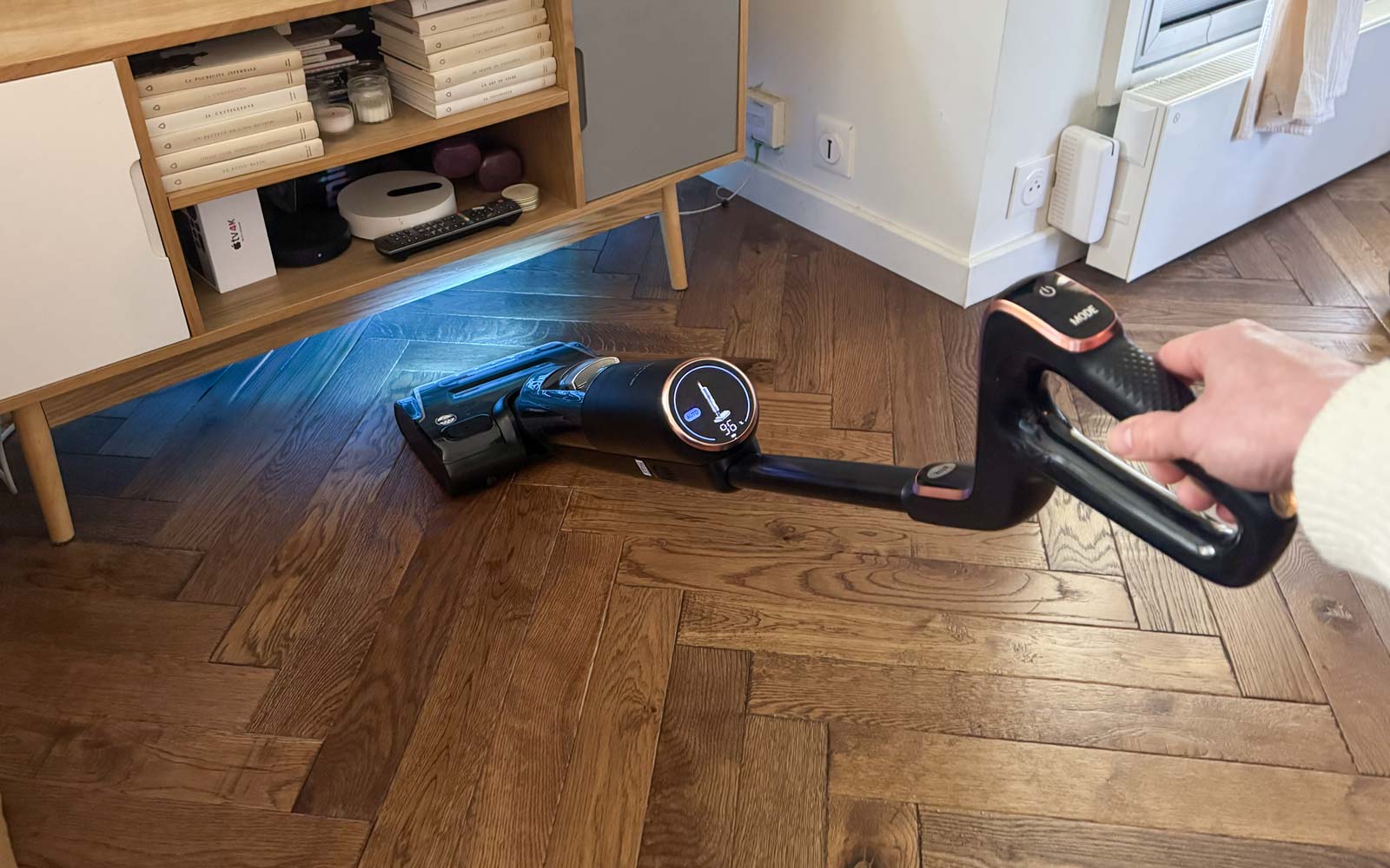 Rowenta X-Clean 7 incliné sous un meuble montrant la limite de fonctionnement lorsque l’appareil est trop penché