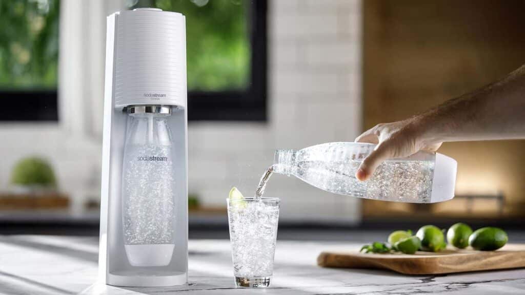 Machine SodaStream Gaia sur un plan de travail avec un verre d’eau pétillante