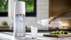 Machine SodaStream Gaia sur un plan de travail avec un verre d’eau pétillante