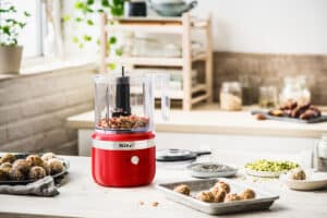 Mini hachoir sans fil KitchenAid 5KFCB519EER rouge avec bol de 1,2 L sur un plan de travail