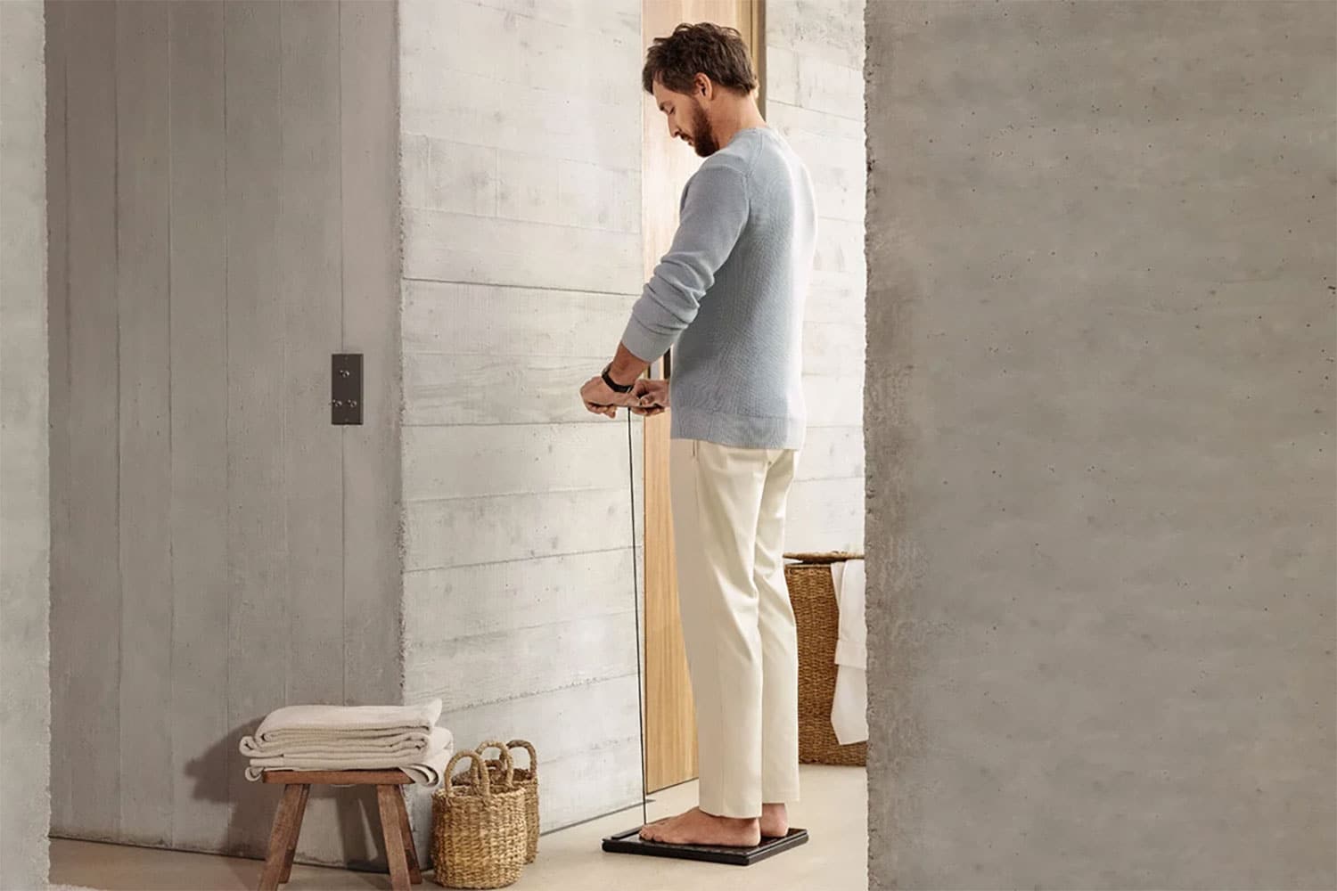 Personne utilisant la balance connectée Withings Body Scan 2 en tenant la poignée équipée de capteurs pour réaliser un bilan de santé complet.