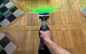 Vue de dessus de l'aspirateur balai Tineco Pure One A90S utilisé sur un parquet en bois.