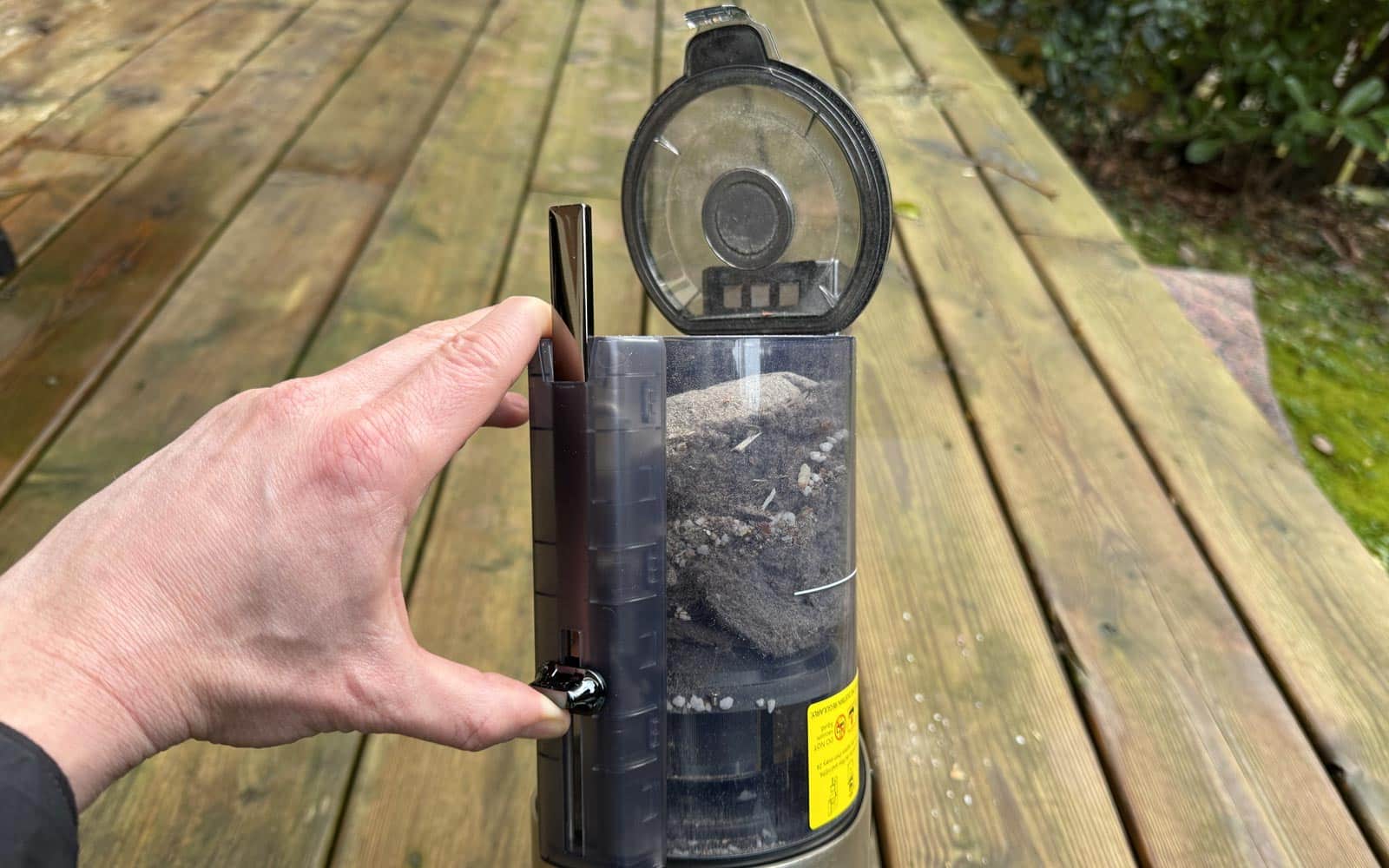 Main ouvrant la trappe du réservoir à poussière de l'aspirateur Tineco.