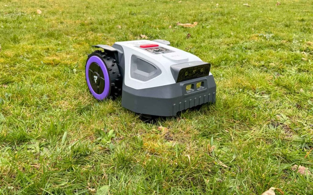 Robot tondeuse compact Anthbot M9 utilisant son système RTK et sa double vision IA dans un passage étroit.