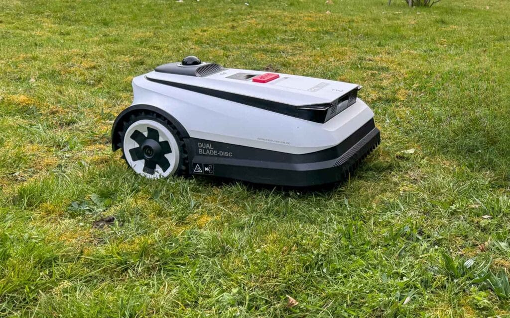Robot tondeuse Ecovacs GOAT A1600 LiDAR PRO tondant au plus près d'une bordure de jardin.