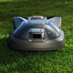 Robot tondeuse Husqvarna Automower sur une pelouse verte, illustrant l'offre d'extension de garantie de 5 ans et la technologie de navigation par vision IA sans câble périphérique.