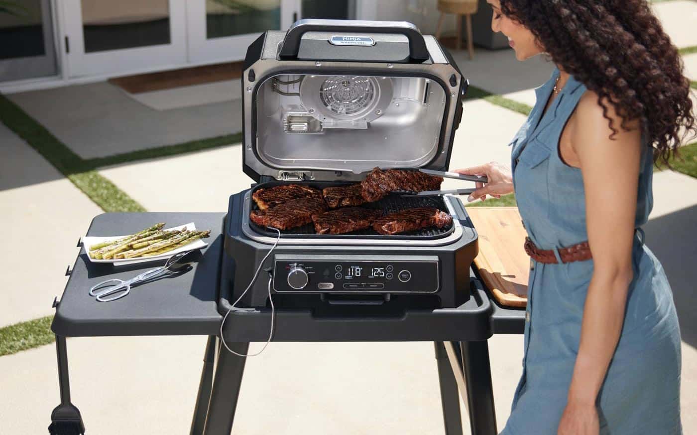 Grande surface de cuisson du barbecue Ninja Woodfire Pro XL remplie de steaks hachés illustrant sa capacité XL.
