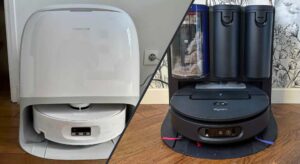 Photographie comparative montrant deux aspirateurs robots laveurs posés côte à côte sur un sol en parquet clair. À gauche, le Roborock Qrevo Curv 2 Flow, de couleur noire et légèrement plus haut, avec son télémètre laser visible sur le dessus. À droite, le Dyson Spot+Scrub Ai, également de couleur noire et grise avec des accents orange caractéristiques de la marque, affichant un design légèrement plus compact. Les deux robots sont orientés de face, permettant de visualiser leurs capteurs et leur caméra frontale.