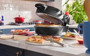 Four à pizza électrique Silvercrest de Lidl ouvert avec une pizza sur la pierre réfractaire et des parts sur un comptoir de cuisine.