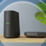 Une Bbox de Bouygues Telecom et son décodeur TV posés sur un meuble en bois avec une plante en arrière-plan, illustrant l'augmentation des tarifs.