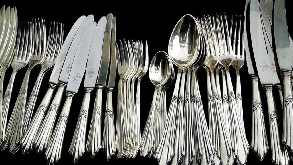 Couverts en argent brillants sur fond noir illustrant une argenterie nettoyée par réaction électrochimique avec aluminium, eau chaude et bicarbonate