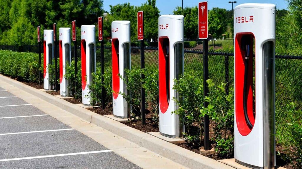 Station de Superchargeurs Tesla sur une aire d'autoroute, un point de recharge essentiel pour les départs en vacances en voiture électrique.