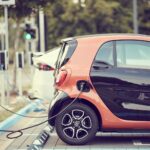 Rangée de bornes de recharge pour voitures électriques installées sur un parking extérieur en bitume d'une résidence en copropriété.