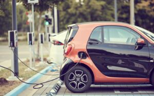 Rangée de bornes de recharge pour voitures électriques installées sur un parking extérieur en bitume d'une résidence en copropriété.