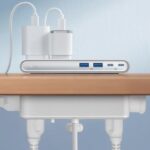 Une multiprise Anker Nano Power Strip à pince blanche fixée sur le bord d'un bureau, montrant ses ports USB et prises secteur.