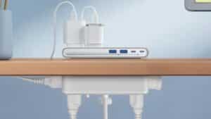 Une multiprise Anker Nano Power Strip à pince blanche fixée sur le bord d'un bureau, montrant ses ports USB et prises secteur.