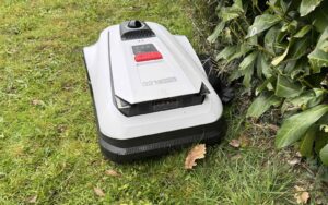 Robot tondeuse Ecovacs Goat A1600 LiDAR PRO coupant l'herbe le long d'une haie.