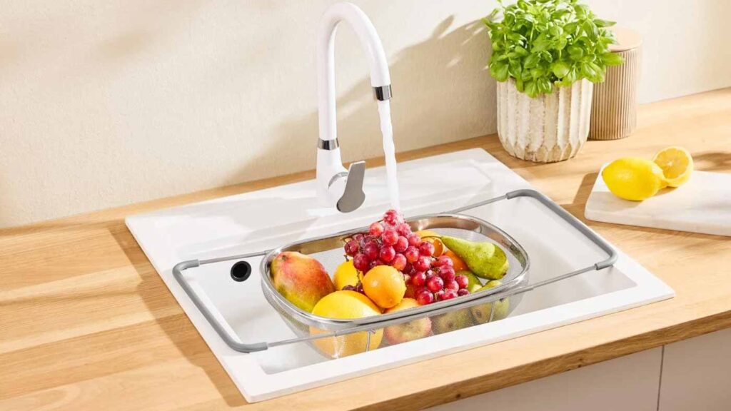 Égouttoir d'évier extensible SilverCrest de Lidl utilisé pour rincer des fruits frais sous l'eau du robinet.
