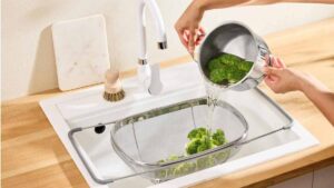 Passoire d'évier Lidl en acier inoxydable positionnée au-dessus du bac pour égoutter des brocolis.