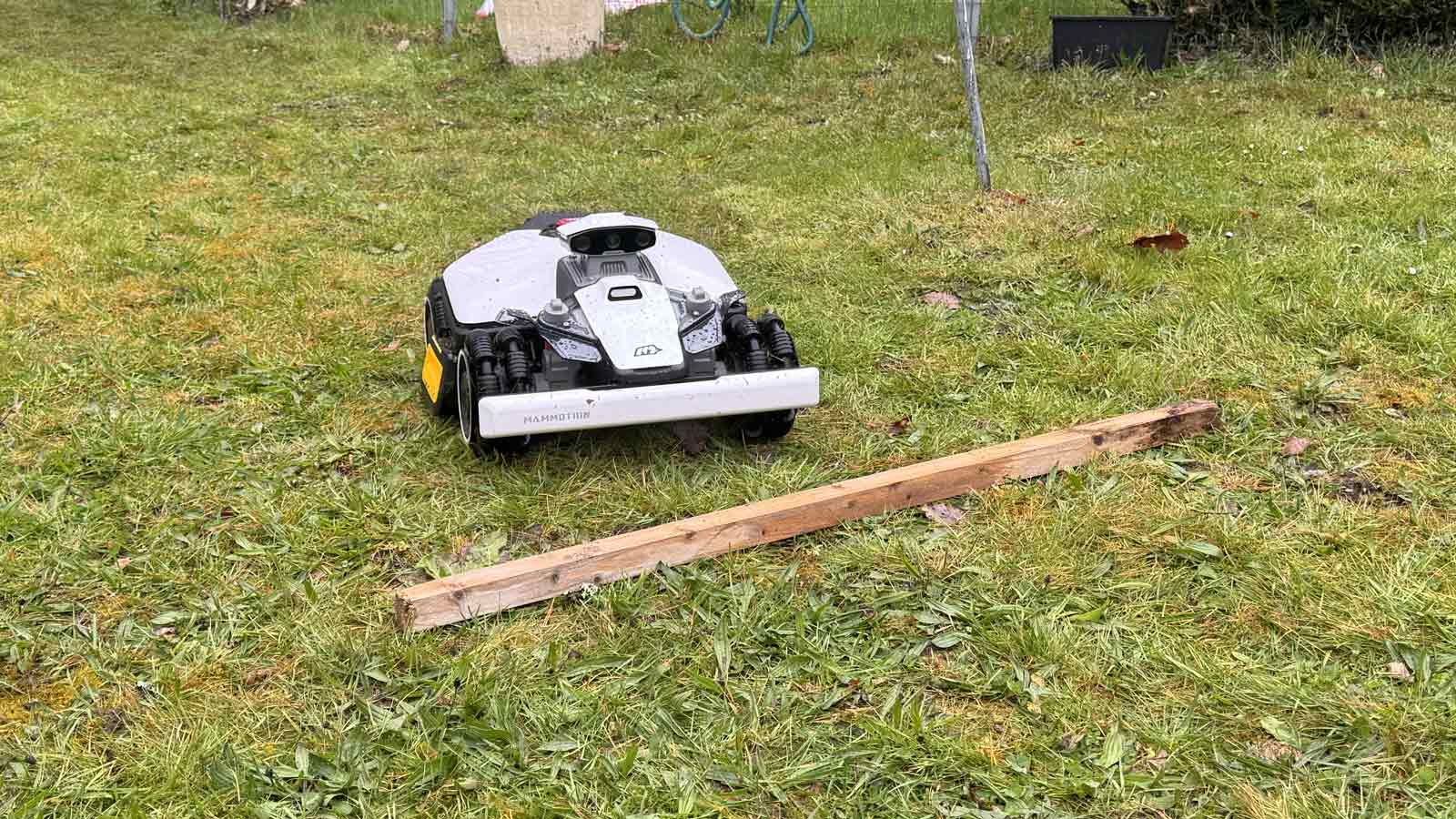 Mammotion Luba Mini 2 AWD évitant un obstacle bas posé sur l’herbe