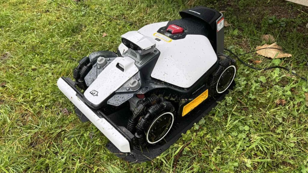 Robot tondeuse Luba Mini 2 AWD rangé dans sa station de recharge au bord de la pelouse