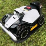 Robot tondeuse Luba Mini 2 AWD rangé dans sa station de recharge au bord de la pelouse