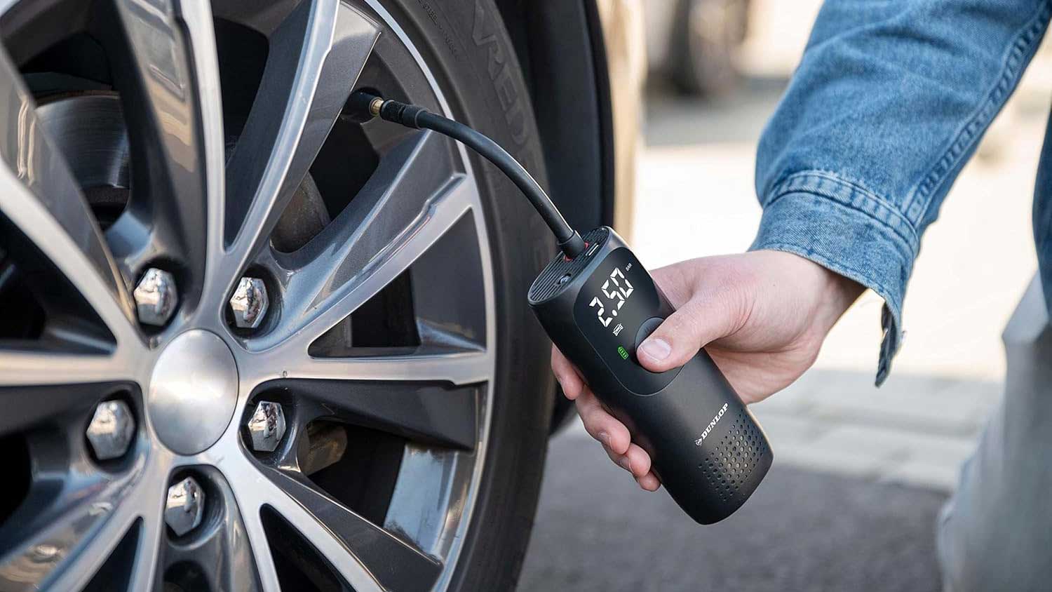 Mini compresseur d'air portatif Dunlop en train de gonfler un pneu de voiture